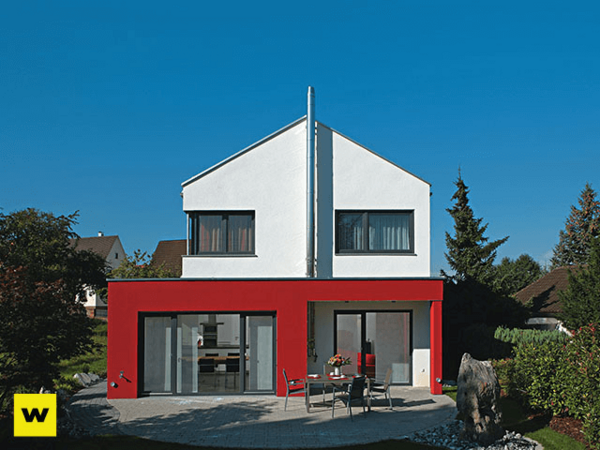 Modernes Einfamilienhaus mit roter Fassade, Garten und großer Fensterfront bei Sonnenschein.