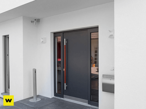 Moderne Haustür aus Aluminium mit Seitenteil, Briefkasten und Überwachungskamera am Eingang.